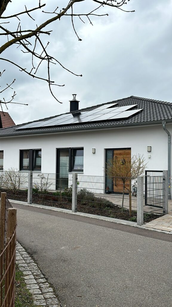 Photovoltaikanlage auf weißem Einfamilienhaus mit Vorgarten